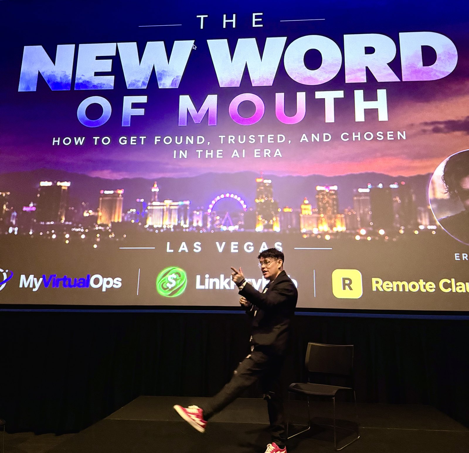Eric Vegas speaking mid gesture on stage, the Las Vegas skyline title slide behind him
